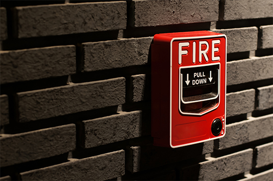 A fire alarm call point box on a brick wall